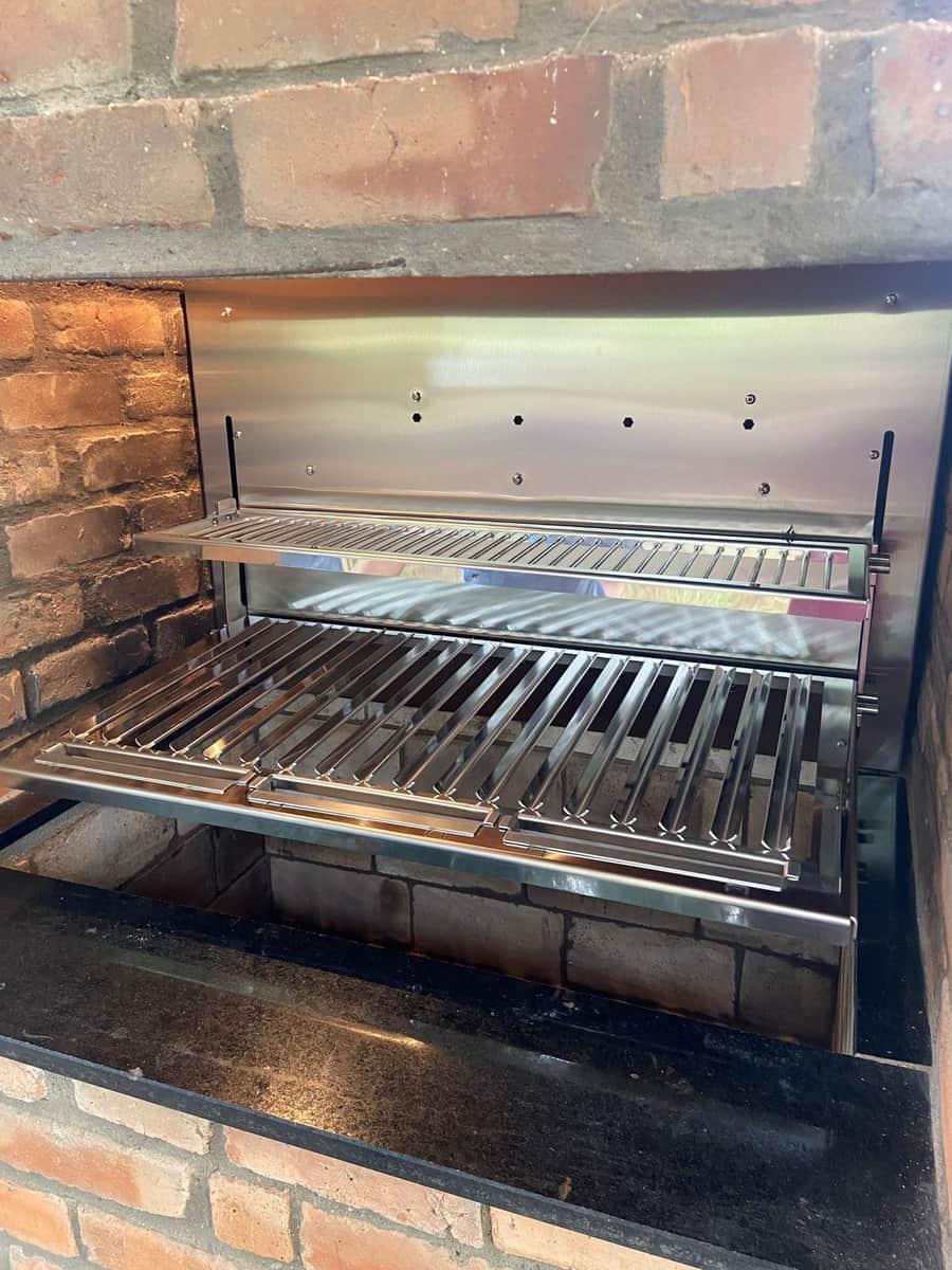 Churrasqueira em inox com acabamento em tijolo e grades